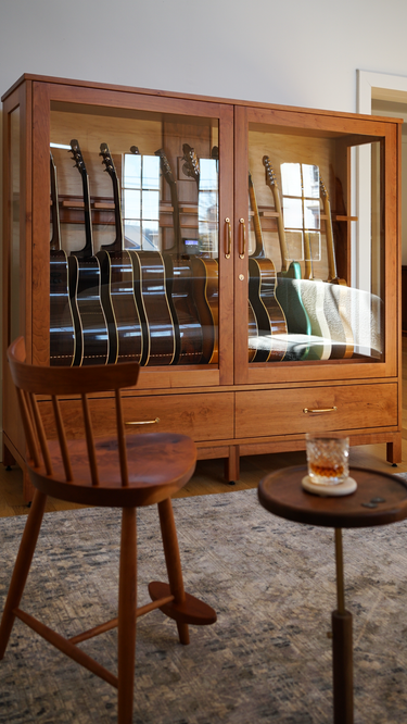 guitar display case in cherry and a guitar player chair together in a music room